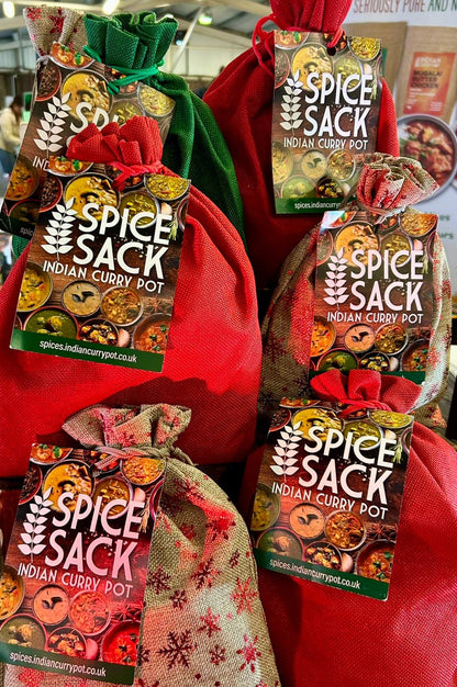 Spice Sack Indian Curry Pot packages displayed on a table with people in the background.